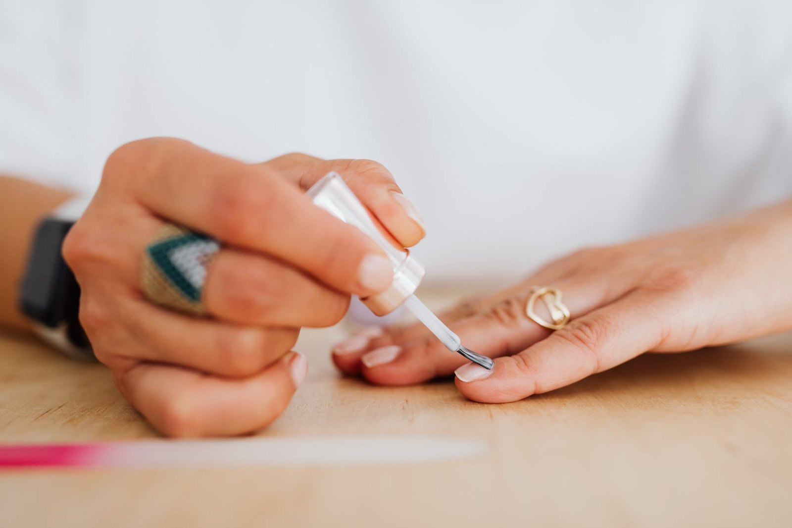 A close-up of a woman applying clear nail polish for a neat manicure.