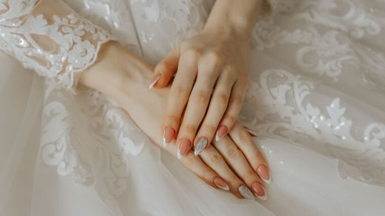 Close-up of a bride's hands on a detailed lace wedding dress, highlighting elegance and beauty.