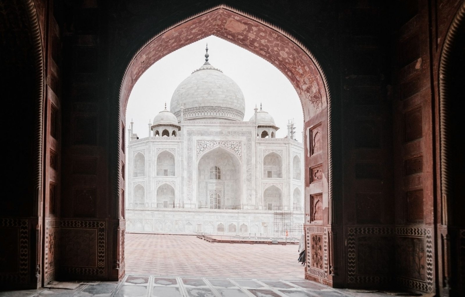 View of the iconic Taj Mahal through a decorative arched doorway, highlighting its architectural brilliance.