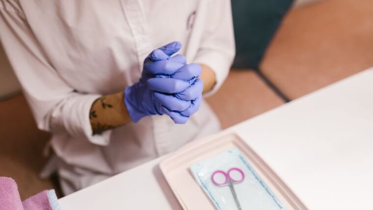 Nail technician wearing gloves preparing for a manicure session in a salon setting.