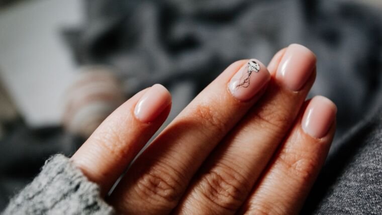 From above of crop unrecognizable female in warm sweater demonstrating hands with manicure with creative nail art